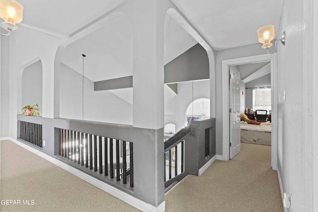 hallway with lofted ceiling and light colored carpet