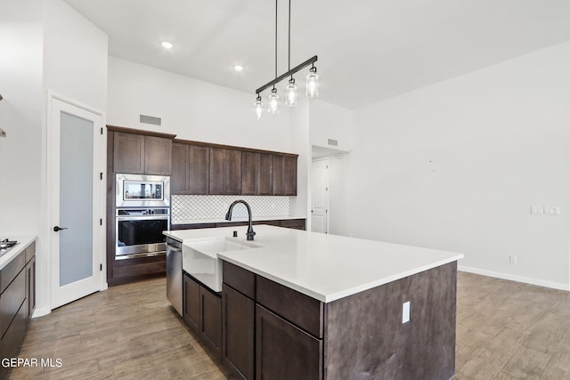 kitchen with light hardwood / wood-style floors, a kitchen island with sink, stainless steel appliances, and sink