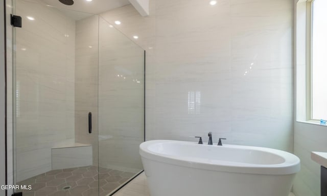 bathroom featuring separate shower and tub and tile walls