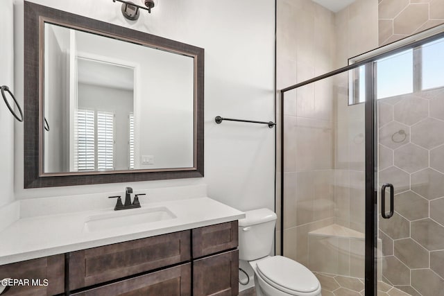 bathroom with vanity, toilet, and a shower with door