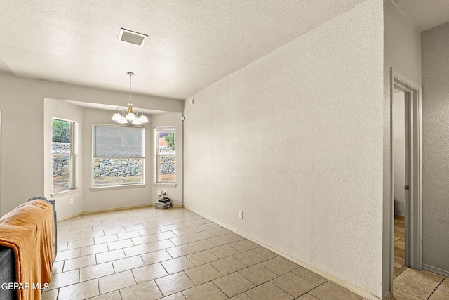 interior space with an inviting chandelier, light tile patterned floors, and a textured ceiling