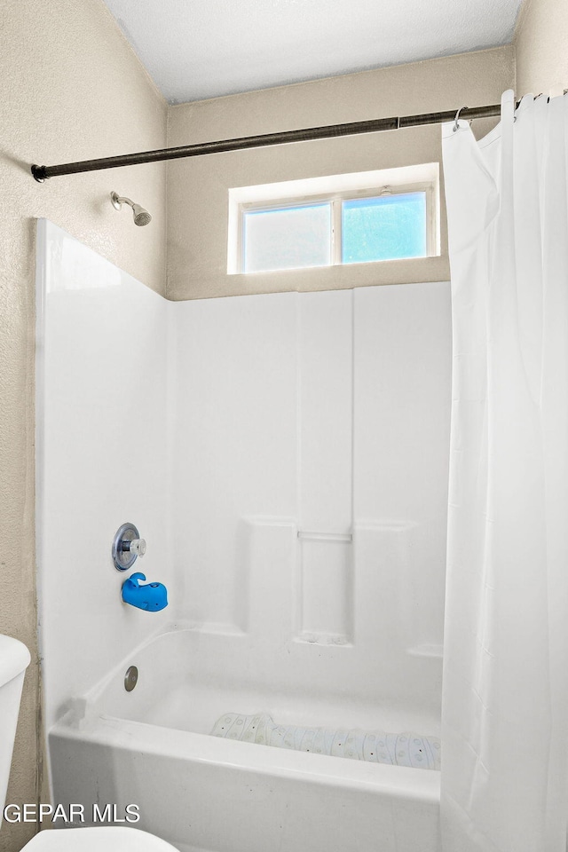 bathroom with shower / bath combo with shower curtain and toilet