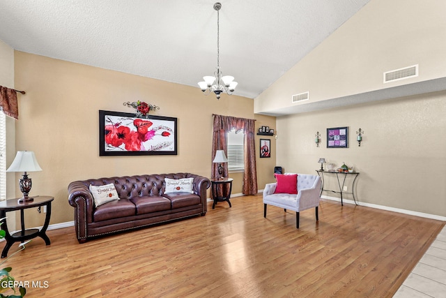 living room with light wood-type flooring, high vaulted ceiling, and a chandelier