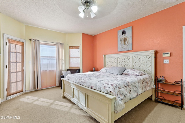 bedroom featuring ceiling fan, light colored carpet, and a textured ceiling