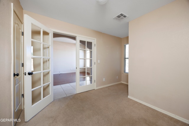 spare room with french doors and light colored carpet