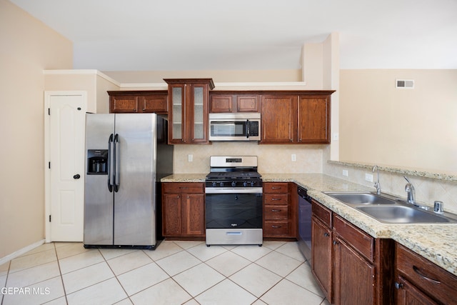 kitchen with light stone counters, tasteful backsplash, sink, appliances with stainless steel finishes, and light tile patterned floors