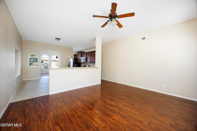 unfurnished living room featuring ceiling fan and dark hardwood / wood-style flooring