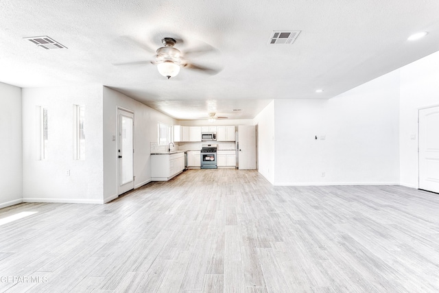 unfurnished living room with light hardwood / wood-style floors and a textured ceiling