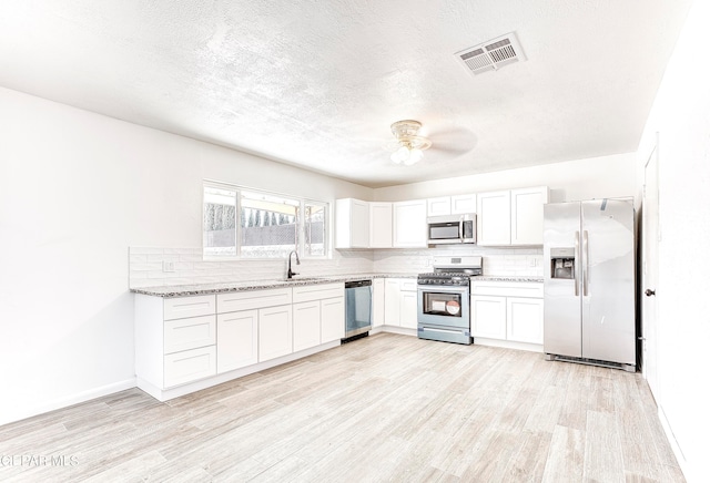 kitchen featuring stainless steel appliances, light hardwood / wood-style floors, light stone counters, and white cabinetry