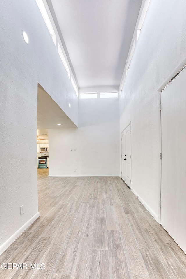 empty room with a towering ceiling and light hardwood / wood-style floors