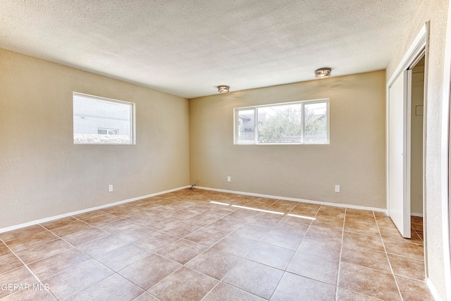 empty room with a textured ceiling and light tile patterned floors