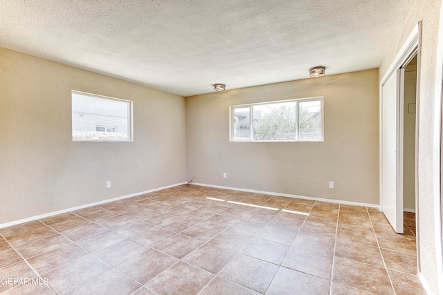 tiled spare room with a textured ceiling