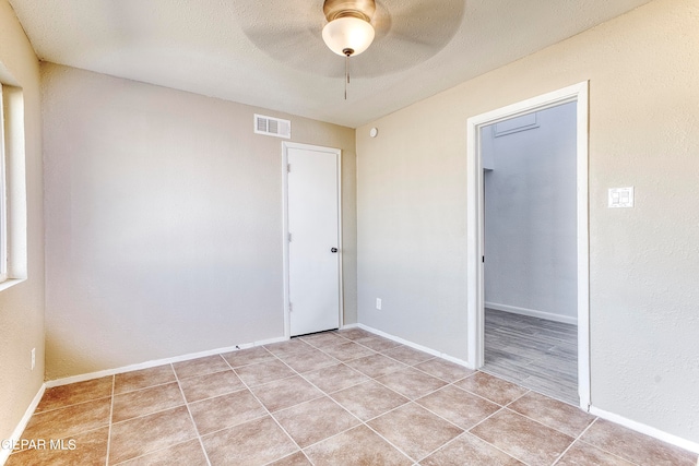 spare room with light tile patterned flooring, ceiling fan, and a textured ceiling