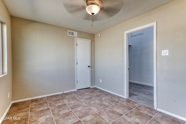 tiled spare room with ceiling fan