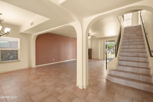 interior space with ceiling fan with notable chandelier and tile patterned floors