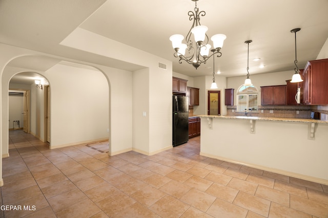 kitchen with a kitchen breakfast bar, hanging light fixtures, black refrigerator, and kitchen peninsula