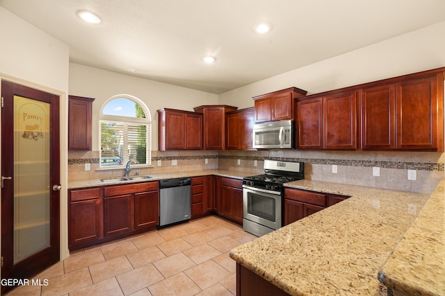 kitchen featuring light stone countertops, decorative backsplash, sink, and stainless steel appliances