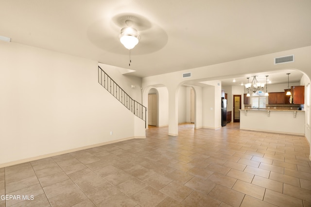 unfurnished living room with ceiling fan with notable chandelier and light tile patterned floors