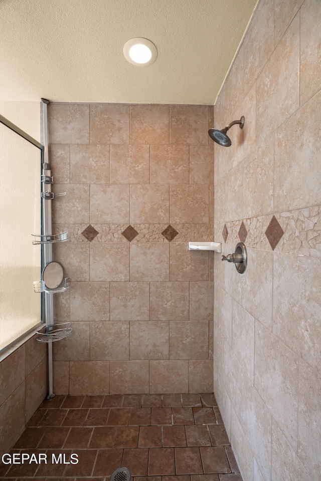 bathroom featuring a tile shower and a textured ceiling