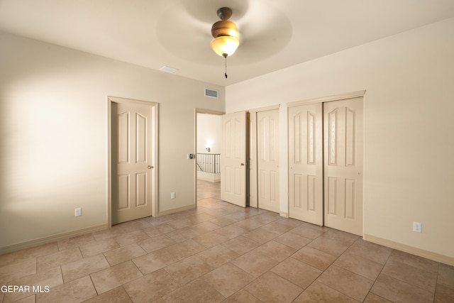 unfurnished bedroom featuring ceiling fan, multiple closets, and light tile patterned floors