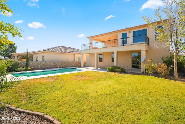 rear view of property with a balcony, a lawn, and a patio area