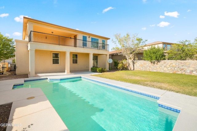 back of property with a patio area, a balcony, and a lawn