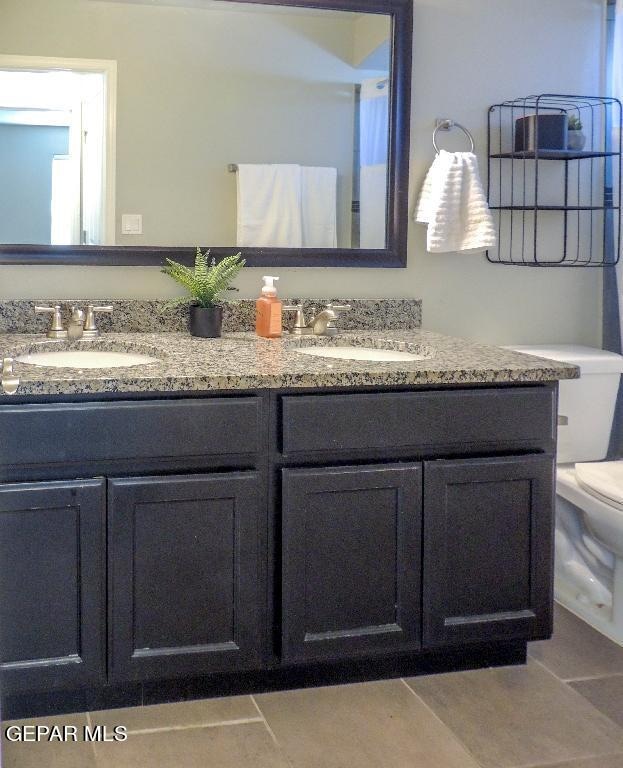 bathroom featuring vanity, toilet, and tile patterned flooring