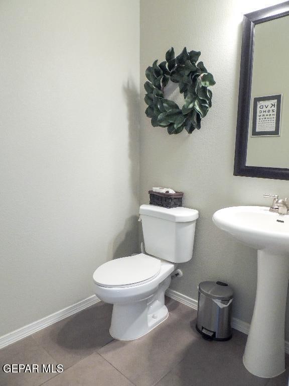 bathroom with toilet, tile patterned floors, and sink