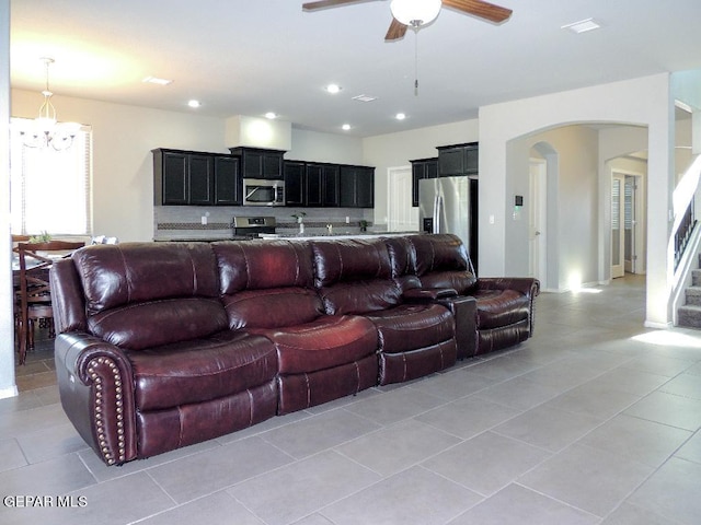 tiled living room featuring ceiling fan with notable chandelier