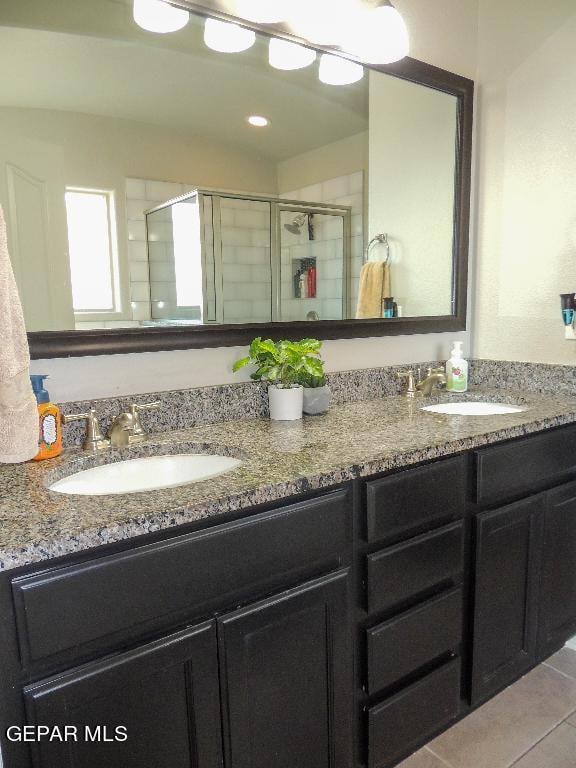 bathroom with a shower with door, vanity, and tile patterned floors