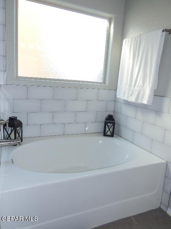 bathroom with tile walls and a bath