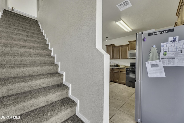 14241 Craggy Rock Ave, El Paso, TX 79938 - staircase featuring visible vents, a textured wall, and tile patterned flooring