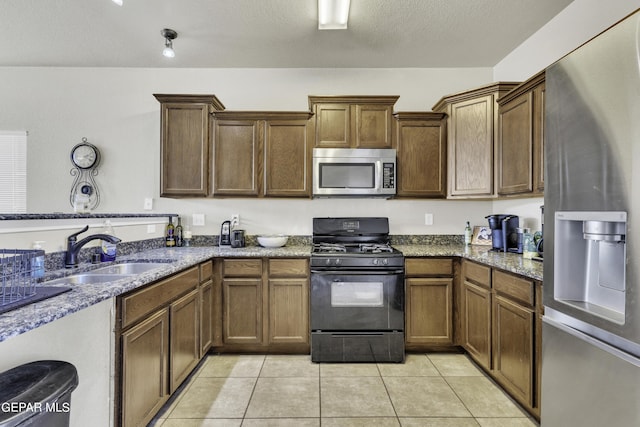 14241 Craggy Rock Ave, El Paso, TX 79938 - kitchen with a sink, stainless steel appliances, light tile patterned floors, dark stone countertops, and a textured ceiling