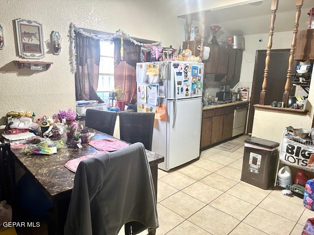 kitchen with white fridge, dark brown cabinetry, light tile patterned floors, and dishwasher