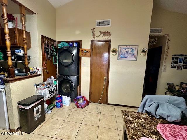 kitchen featuring light tile patterned floors, vaulted ceiling, and stacked washer / drying machine