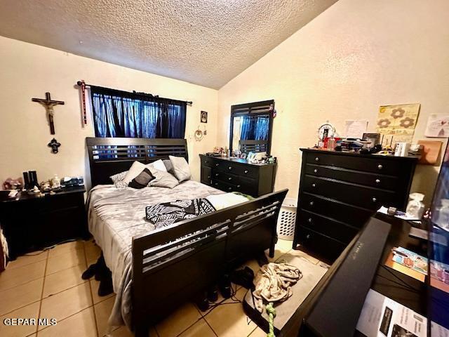 tiled bedroom with vaulted ceiling and a textured ceiling