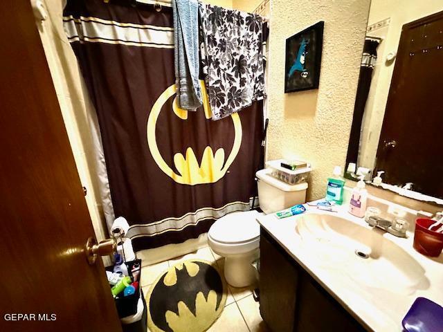 bathroom featuring tile patterned flooring, a shower with curtain, vanity, and toilet