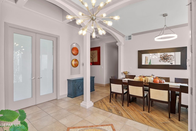 dining area with decorative columns, a chandelier, french doors, and light hardwood / wood-style floors