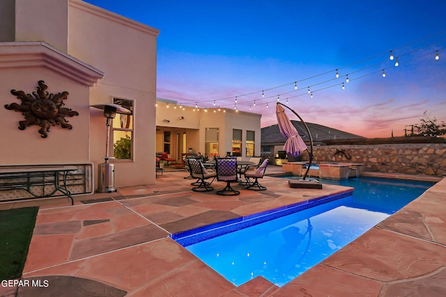 pool at dusk featuring a patio