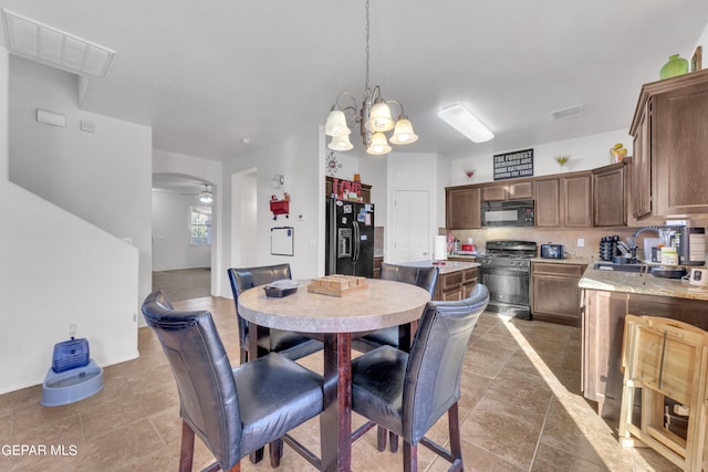 dining space featuring ceiling fan with notable chandelier and sink