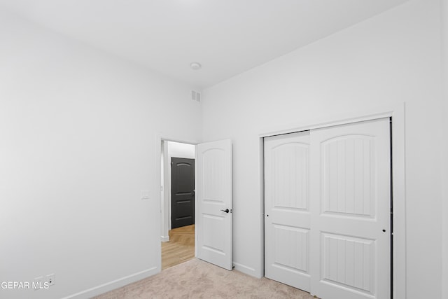 unfurnished bedroom with light carpet and a closet