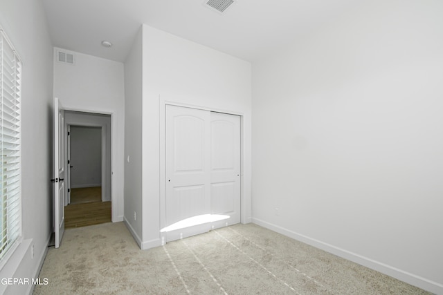 unfurnished bedroom with a closet and light colored carpet