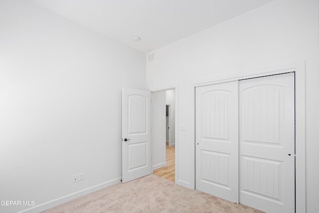 unfurnished bedroom featuring a closet and light carpet