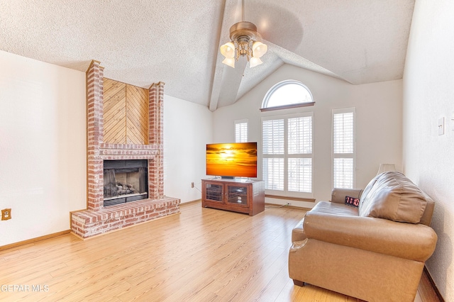 living room featuring ceiling fan, lofted ceiling, a textured ceiling, hardwood / wood-style flooring, and a fireplace