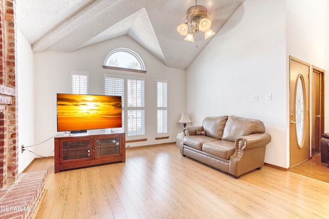 living room featuring light hardwood / wood-style floors, high vaulted ceiling, a textured ceiling, and ceiling fan