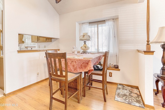 dining area with a textured ceiling, vaulted ceiling, and light hardwood / wood-style flooring