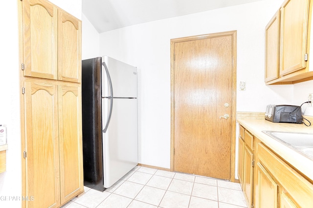 kitchen with stainless steel fridge, light tile patterned flooring, and light brown cabinets