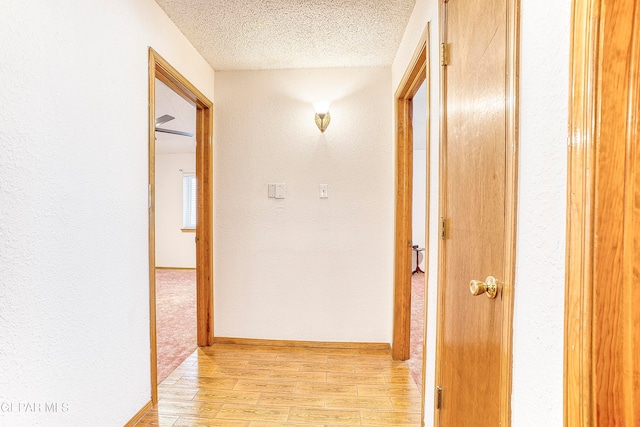 hallway featuring light hardwood / wood-style floors and a textured ceiling