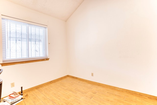 spare room with vaulted ceiling and hardwood / wood-style flooring