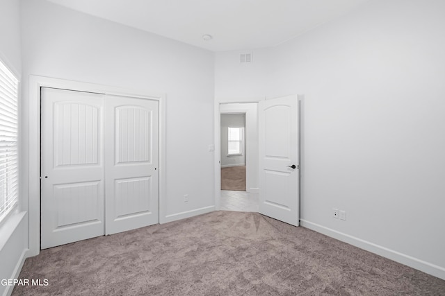 unfurnished bedroom with light colored carpet and a closet